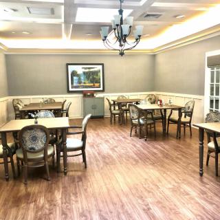 A well-lit dining room with elegant tables and chairs arranged on a wooden floor.