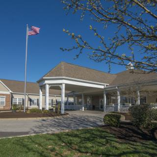 The entrance to a building with an American flag flying on a clear day.
