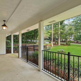 A spacious covered porch overlooking a lush garden with trees.