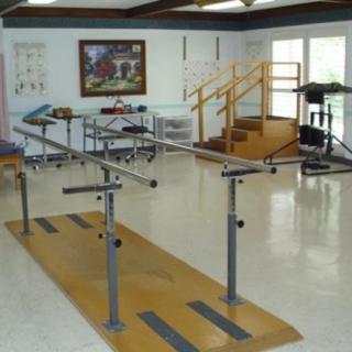 A rehabilitation room equipped with parallel bars and other physical therapy equipment.