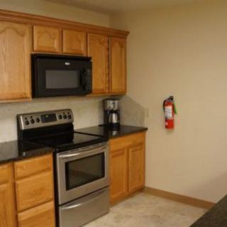 A kitchen with wooden cabinets and modern appliances including a microwave, oven, and coffee maker.