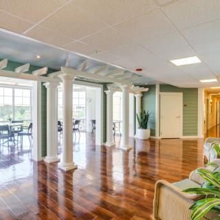 A spacious and modern lobby area with hardwood floors, decorative columns, and large windows.