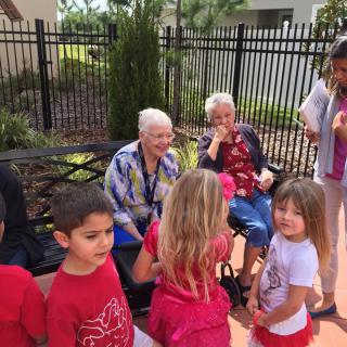 A group of children interacting with older adults outdoors, showcasing a community gathering.