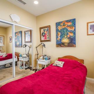 Cozy bedroom with a red blanket, decorated with artwork and mirrored closet doors.