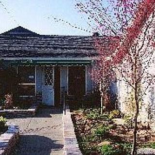A cozy house with a garden and patio, surrounded by trees in spring bloom.