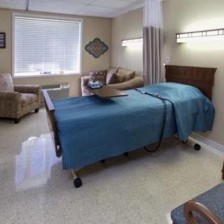 A hospital room with a bed and seating area.