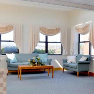 A cozy living room with elegant curtains, a comfortable sofa and armchair, and a wooden coffee table.