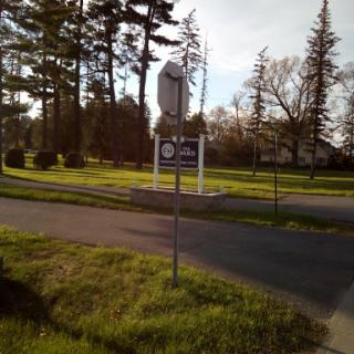 A street sign surrounded by trees and grass in a peaceful area.