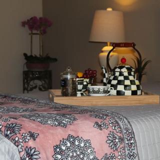 A cozy bedroom setting with a decorative teapot and tray on the bed.