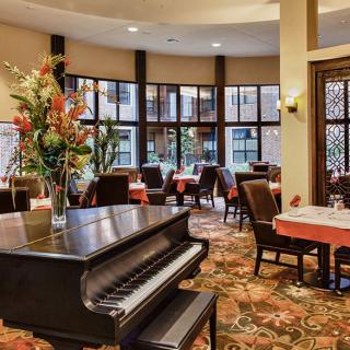 A beautifully decorated dining area featuring a grand piano and elegant floral arrangements.