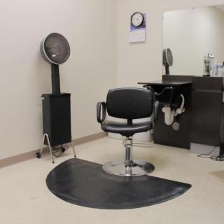 An empty hair salon setup with a styling chair, mirror, and hair dryer.