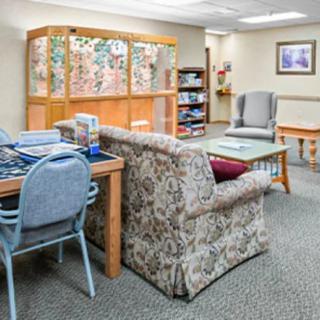 A cozy waiting room with comfortable seating, a bookshelf, and a table.