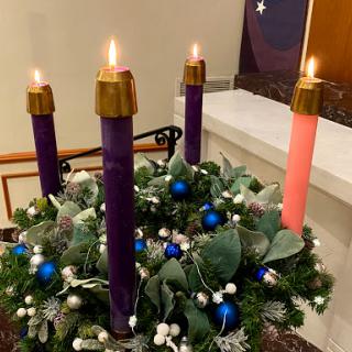 An Advent wreath featuring four lit candles, symbolizing the countdown to Christmas.
