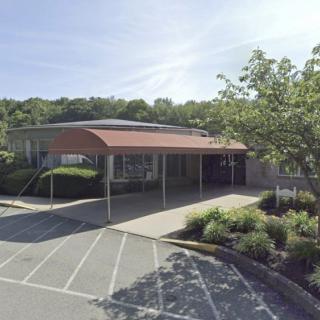 An exterior view of a building with a covered entrance and surrounding landscaping.