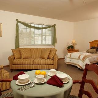 A cozy hotel room featuring a comfortable sofa, a neatly made bed, and a table set for dining.
