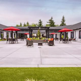 Spacious outdoor patio area with red umbrellas and comfortable seating.