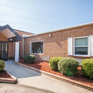 A brick building with a landscaped entrance and windows on a sunny day.