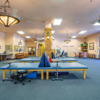 A spacious rehabilitation and physical therapy room equipped with exercise tables and tools.
