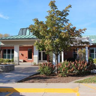 A small commercial building surrounded by landscaped greenery and a clear blue sky.