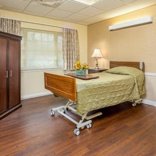 A well-furnished hospital room with a bed, wardrobe, and window.