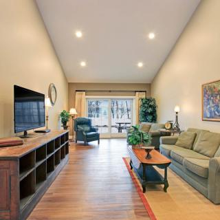 A cozy living room featuring a sofa, television, and coffee table with elegant lighting and decor.