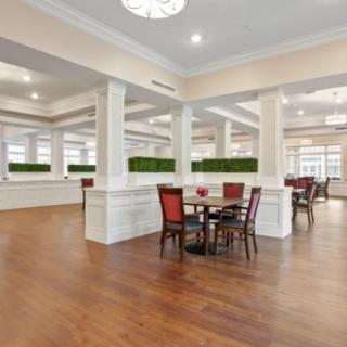 A spacious and modern dining area with tables and chairs arranged on a wooden floor.