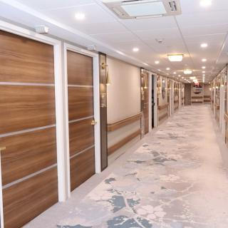 A modern, well-lit hallway featuring wooden doors and a patterned floor.