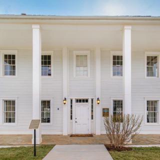 A two-story white building with columns and large windows.