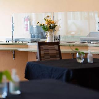 A dining area with elegantly set tables and a flower arrangement in the background.