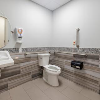 A modern accessible bathroom featuring a toilet, sink, and hand dryer.