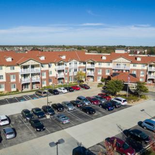 Aerial view of a residential apartment complex with a parking lot in front.