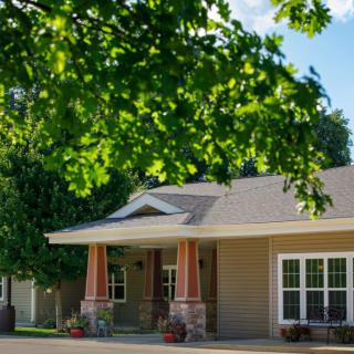 A charming house with a front porch surrounded by lush green trees.
