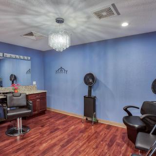 A stylish hair salon interior with blue walls and a chandelier.