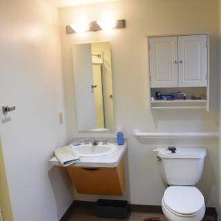 A compact bathroom featuring a sink, toilet, and mirror with storage cabinets.
