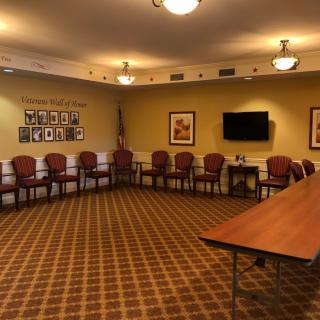 An empty conference room with arranged chairs, a mounted television, and decorative wall art.
