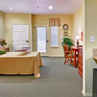 A cozy and inviting living space featuring a bed, desk, and natural light.