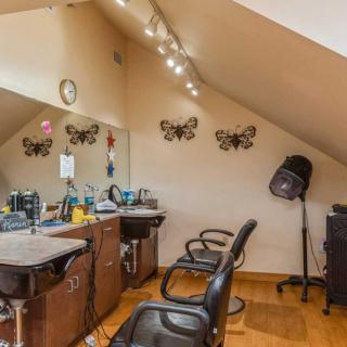A cozy hair salon setup with chairs, mirrors, and hair styling equipment under warm lighting.