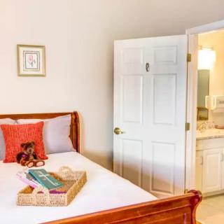 A cozy bedroom with an adjacent bathroom, featuring a bed with colorful pillows and a tray on top.