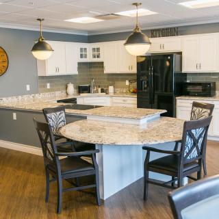 A modern kitchen featuring a central round table with chairs, stylish lighting, and sleek countertops.
