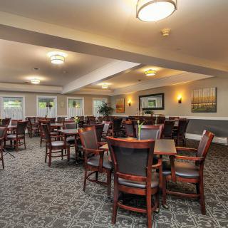 A well-lit dining area with multiple tables and chairs, carpeted floors, and wall decor.