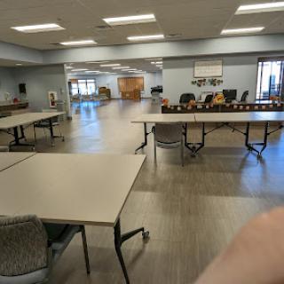 A spacious community room set up with tables and chairs, ready for an event.
