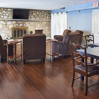 A cozy living room with comfortable chairs, a stone fireplace, and a television on the wall.
