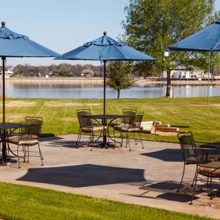 Outdoor patio area with tables and umbrellas overlooking a lake.