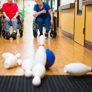 Seniors enjoying a fun bowling activity in a rehabilitation center.