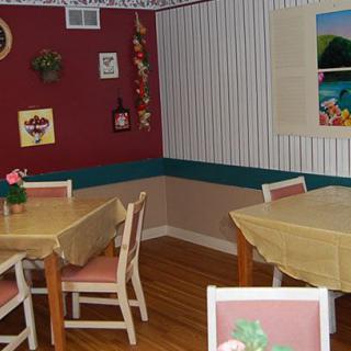 A cozy dining area with neatly arranged tables and chairs, adorned with wall art and decorative items.