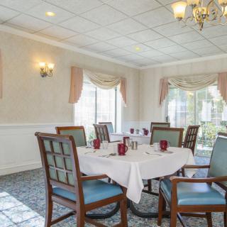 A well-appointed dining room with a set table, elegant chairs, and large windows.