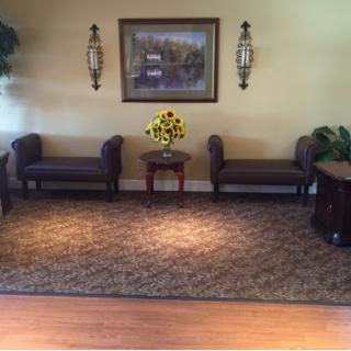 A cozy and inviting lobby area featuring comfortable seating, decorative plants, and a vibrant flower arrangement.