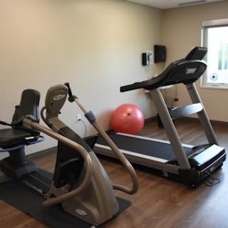 A small home gym featuring a treadmill, elliptical machine, and a fitness ball.