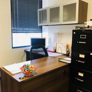 A neat office workspace with a desk, computer, and filing cabinet.