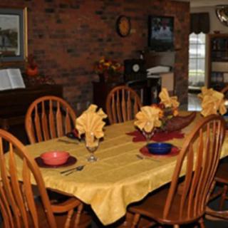 A dining room with a table set for six, featuring yellow napkins and various colored bowls.